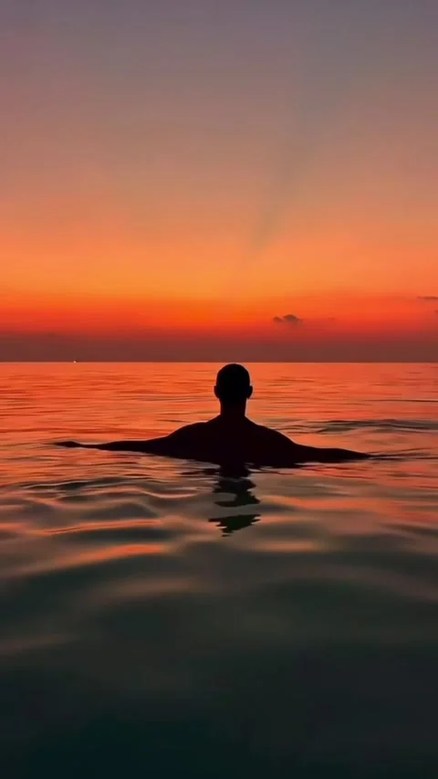 Red Sky Reflected on Water with Figure in Ocean Stockbeeldmateriaal 327800034