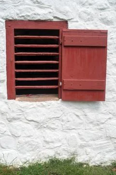Red slatted window and shutter on whitewashed colonial stone wall. Foto stock