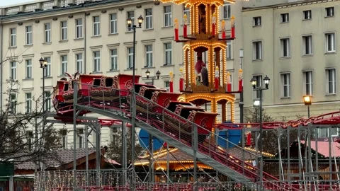 A red sleigh roller coaster moves around a lit Christmas pyramid at a festive Stock Footage 345831763