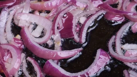 Red sliced onion is fried in vegetable oil hot frying pan Stock Footage 311787437