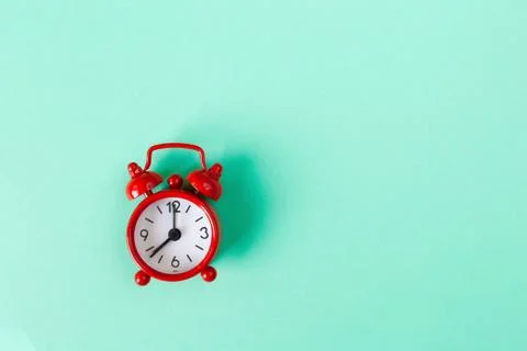 Red small alarm clock on mint color background with copy space. Minimal style Stock Photos