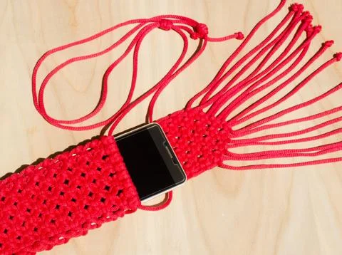 Red small bag knitted using macrame technique for a mobile phone. Stock Photos