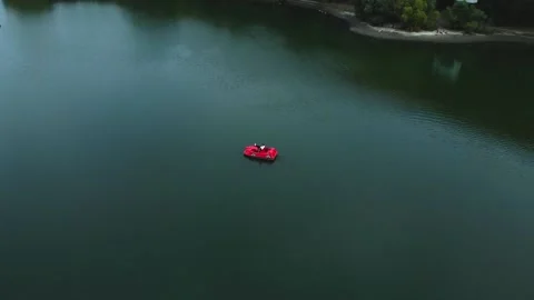 A red small catamaran is float on the surface of the lake Stock Footage 218219012