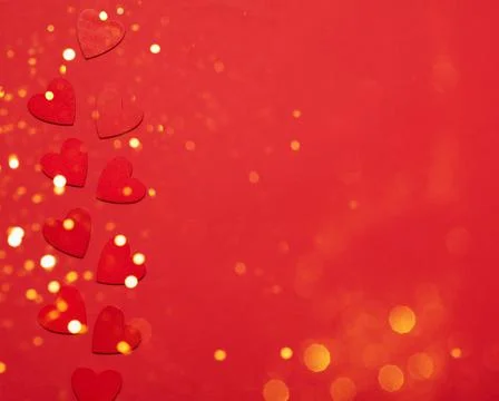 Red small hearts on a red background with sparkles and confetti. Festive Stock Photos