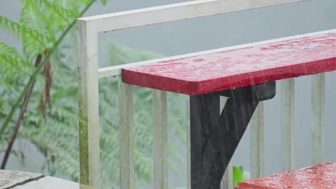 Red Small Table by Fence During Rainy Weather Creating Moody Urban Atmosphere Stock Footage 306193514
