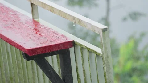 Red Small Table by Fence During Rainy Weather Creating Moody Urban Atmosphere Stock Footage 306193569