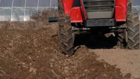 Red small tractor in the field plowing close up Stockbeeldmateriaal 187618843