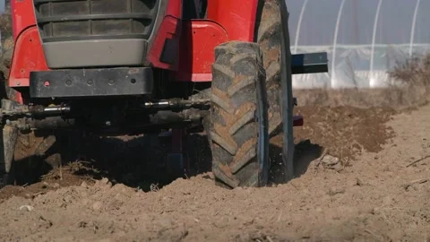 Red small tractor in the field plowing close up Stockbeeldmateriaal 187618868