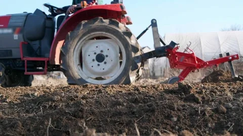 Red small tractor in the field plowing close up Stockbeeldmateriaal 187619690