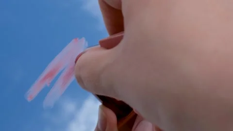 Red smear of lipstick against the background of the sky and clouds close-up. Stock Footage 250297930