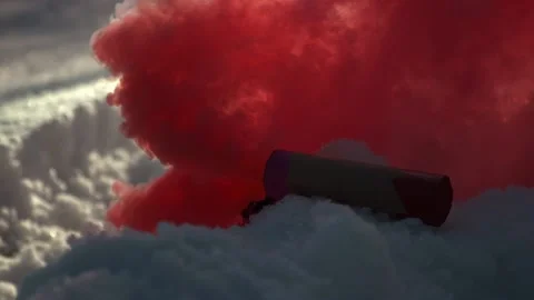 A red smoke bomb is lying on the snow, thick red smoke, slow motion Stock Footage 210036202
