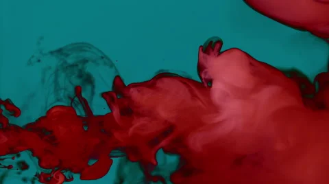 Red smoke on a dark turquoise background moving from left creating volutes Stock Footage 65331045