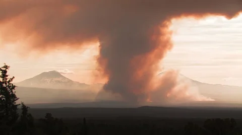 RED SMOKE RISES ABOVE FOREST FIRE WITH MOUNTAINS IN BACKGROUND Stock Footage 53348899