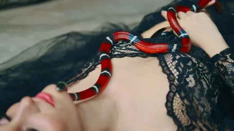 Red snake boa constrictor crawls over body of woman princess. Sleeping beauty Video stock 178992403