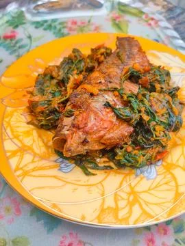 Red Snapper Fish cooked with spicy sambal, and Green Onions, Tomatos and Ba.. Stock Photos