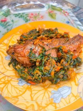 Red Snapper Fish cooked with spicy sambal, and Green Onions, Tomatos and Ba.. Stock Photos