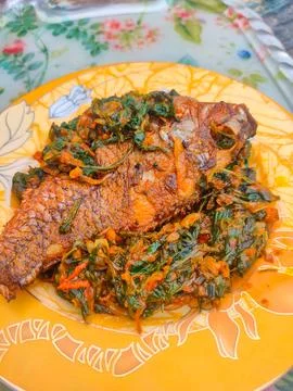 Red Snapper Fish cooked with spicy sambal, and Green Onions, Tomatos and Ba.. Stock Photos