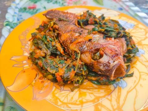 Red Snapper Fish cooked with spicy sambal, and Green Onions, Tomatos and Ba.. Stock Photos