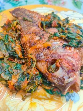 Red Snapper Fish cooked with spicy sambal, and Green Onions, Tomatos and Ba.. Stock Photos
