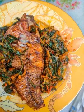 Red Snapper Fish cooked with spicy sambal, and Green Onions, Tomatos and Ba.. Stock Photos