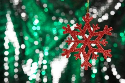Red snow flake on a green, silver glitter background Stock Photos