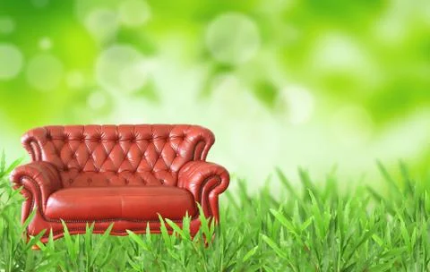 Red sofa on the grass field Stock Photos