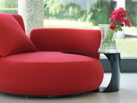 Red sofa with round side table and red flowers Stock Photos