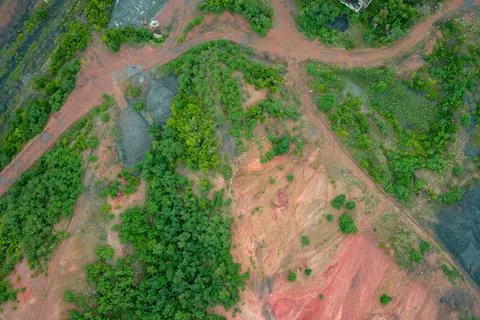 Red soil degradation and mining waste land with green trees nature reclamation Stock Photos