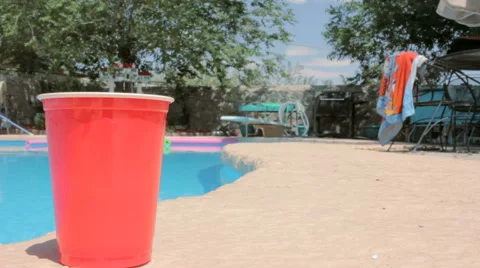 Red Solo Cup Sits Poolside Next to a Swimming Pool Stock Footage 64111785