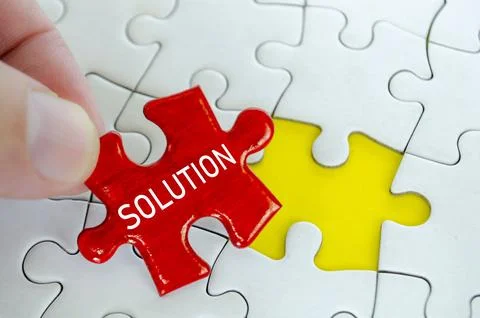 Red solution puzzle piece being placed by hand beside a yellow piece on a w.. Stock Photos