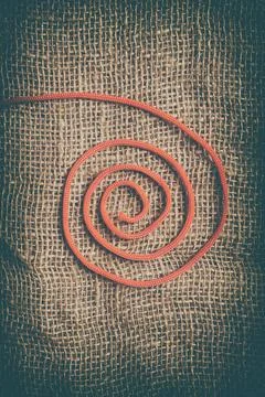 Red spiral thread on jute background. Abstract and vertical image ideal for a Stock Photos