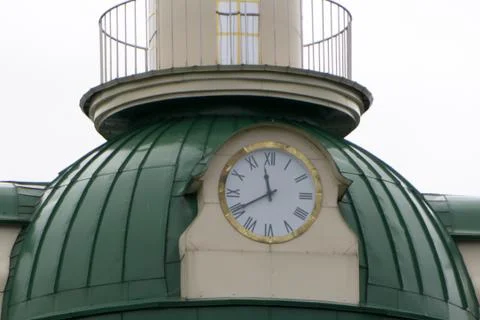 Red spire with wind vane and clock on a red brick building Stock Photos