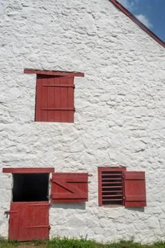 Red split colonial door and windows on whitewashed stone facade. Stock Photos