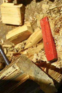 Red splitting wedge embedded in firewood log during wood processing Stock Photos