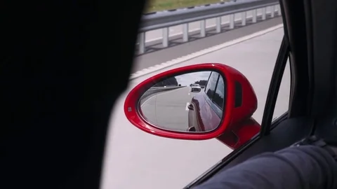 Red sport car rides on the road, a view of the side rearview mirror. Stock Footage