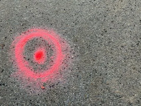 Red spray paint marking circle on asphalt surface Stock Photos
