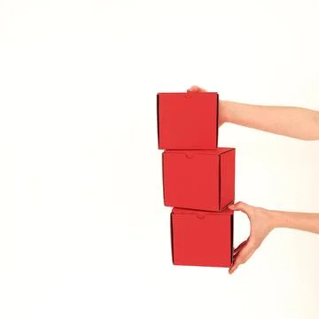 Red square craft boxes hold human hands on a white background. Place for te.. Stock Photos