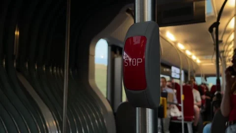 Red stop button on pole inside passenger bus with blurred seated commuters and Vidéo 344587001