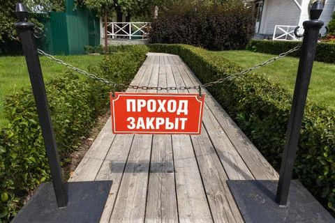 A red stop sign hangs on a chain across a wooden boardwalk Stock Photos