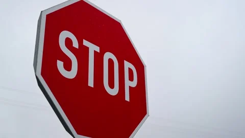 Red Stop Sign Under Cloudy Sky Symbolizing Road Safety and Caution 스톡 동영상 319000214