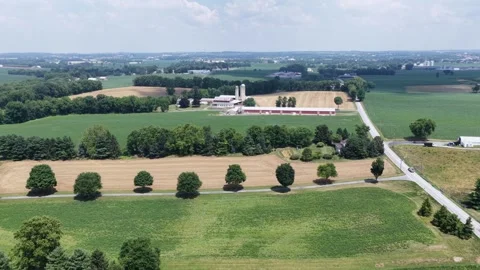 Red storage barn and grain silos stand beside golden wheat fields in American Stock Footage 340938558