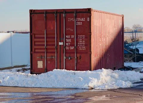 Red storage crate freit container sitting behind a small snowbank Stock Photos