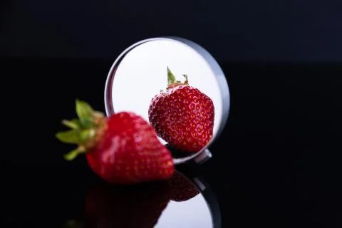 Red strawberries on a black background with reflection in the mirror. The con Stock Photos
