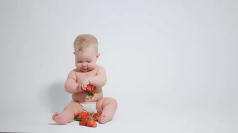 Red strawberries in the hands of a 6 month old baby. video filmed on a white  스톡 동영상 242780313