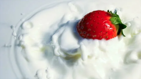 Red strawberry falling in milk in slow motion. 库存影片 145349816