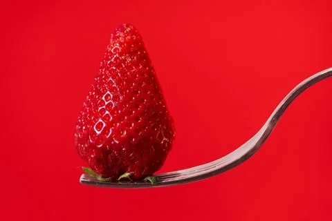 Red strawberry on fork with red display background Stock-Fotos