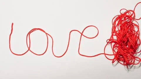 Red string forming the word love with tangled yarn on white background Stock Photos