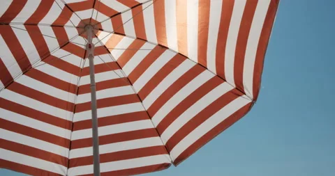 Red stripe umbrella on a solid blue sky on a beach. Sunny day on vacation. Stock-Footage 143211177