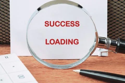Red SUCCESS LOADING on a document, set on a wooden desk with office essential Stock Photos