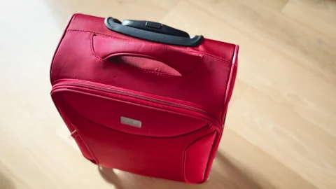 Red Suitcase Rolling into Frame on Clean Background Stock Footage 307679012